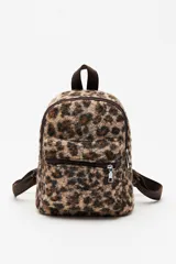 Mochila compacta con estampado animal print de textura suave y esponjosa. Cuenta con un bolsillo frontal con cierre, correas ajustables y asa superior en color marrón.
