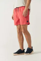 Short de baño liso color coral con cintura elástica, cordón ajustable, dos bolsillos laterales y uno trasero.