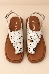 Sandalias planas de cuero color dorado champagne, con capellada de diseño tejido, tira separadora de dedos y tira ajustable en el talón con hebilla metálica.