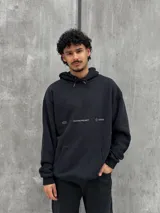 Canguro negro con capucha ajustable con cordones, bolsillo tipo canguro y estampado frontal con el texto "Crafted Project" y símbolos gráficos.