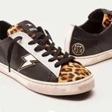 Zapatillas bajas de cuero vacuno negro con puntera de cuero con pelo de leopardo. Aplique lateral de rayo de cuero blanco con contorno dorado. Cordones de algodón encerado y suela de caucho con banda cosida.