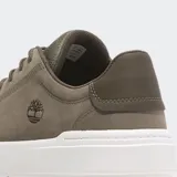 Zapatilla urbana Timberland modelo Seneca Bay, color verde oliva/marrón topo, con capellada de nobuk o cuero sintético y suela blanca gruesa. Presenta el logo del árbol de Timberland grabado en el lateral.