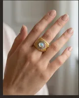 Anillo ancho de bronce con baño de oro, diseño texturizado con aplique central en forma de flor con circonias engarzadas y piedra natural ovalada.