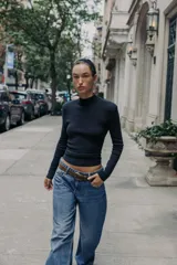 Jersey de punto de cuello subido y manga larga con hombreras. Presenta un diseño de espalda abierta con detalle de nudo.