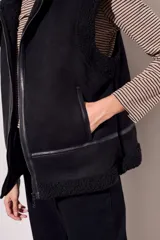 Chaleco negro con cuello de piel sintética, cierre frontal con cremallera y corte oversize.