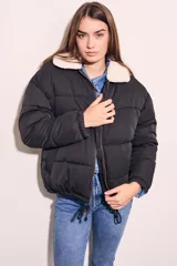 Campera puffer negra con cuello de corderito color crema, cierre frontal con cremallera y cordón ajustable en el ruedo.