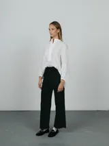 Pantalón de corte recto y tiro alto, color negro, con cierre frontal y bolsillos laterales.