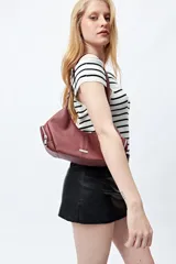 Cartera de hombro color bordó, de símil cuero, con diseño curvo y detalles de cierres metálicos en los extremos.