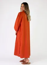 Vestido camisero largo de color naranja, con mangas largas abullonadas y cierre frontal de botones.