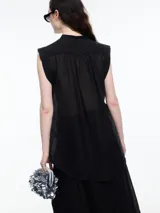 Camisa negra sin mangas con cuello mao y cierre frontal con botones.