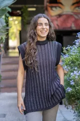 Chaleco tejido de punto acanalado vertical en color negro con hilos de lurex plateados. Presenta cuello redondo, hombros amplios con efecto de hombrera caída y tajos laterales en el ruedo.