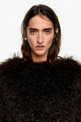 Cazadora corta de pelo sintético con textura afelpada, cuello redondo y cierre frontal con cremallera metálica.