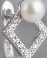 Aros tipo argolla con diseño geométrico en forma de rombo, engastados con pequeñas circonias brillantes y rematados con una perla blanca. Fabricados en plata 925.