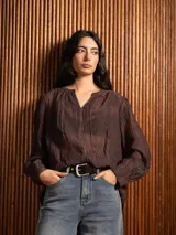 Blusa de tela liviana color bordó, con escote en V y detalles de bordado floral tono sobre tono. Presenta mangas largas con leve volumen y puños abotonados.