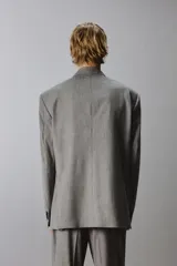 Blazer de corte regular confeccionada en tejido con lana, color gris. Presenta cuello con solapas de muesca, manga larga, bolsillos de vivo en el pecho y bolsillos de solapa en la cadera. Cuenta con cierre frontal de botones y aberturas en la espalda.