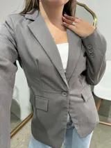 Blazer sastrero de corte clásico en color gris, con solapas de muesca, cierre frontal de un botón y bolsillos laterales con solapa.