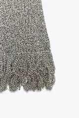 Jersey de punto gris jaspeado, de manga corta y escote redondo. El bajo presenta un acabado deshilachado o con flecos.