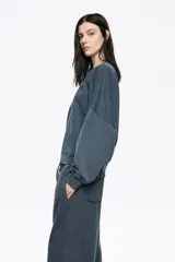 Buzo de algodón color negro con efecto gastado, corte globo y mangas largas ranglán. Presenta un logo bordado discreto en el pecho.