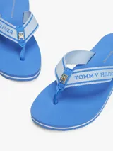 Ojotas de mujer color azul vibrante con suela de EVA de dos capas, separadas por una fina línea blanca. Las tiras son de tejido trenzado en tonos de azul claro y llevan la inscripción tonal "Tommy Hilfiger".