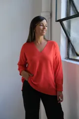 Sweater de punto color naranja, con cuello en V, manga larga y diseño holgado con tajos laterales en el ruedo.