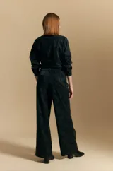 Pantalón de corte ancho y silueta relajada, confeccionado en tejido de efecto gamuzado color marrón oscuro. Presenta un diseño de tiro alto con cierre frontal y bolsillos laterales.