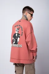 Buzo de tejido friza color crema, de corte oversize y cuello redondo. Presenta un pequeño bordado o parche en el pecho izquierdo con un diseño de cabeza de animal en tonos rojizos/terracota.