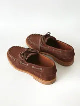 Sandalias de cuero gamuzado color marrón chocolate, diseño tipo huarache con tiras entrelazadas, tira en el empeine, talón cerrado y hebilla metálica de ajuste lateral.