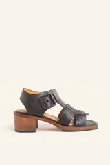 Sandalia de cuero vacuno texturado color negro, con tiras anchas y hebilla lateral. Taco ancho de madera.