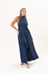 Vestido largo azul de tafeta con textura corrugada, cuello halter, espalda descubierta y falda amplia con tajo lateral y volados.