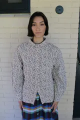 Sobrecamisa de paño con estampado de cuadros vichy en blanco y negro, de corte entallado, cuello clásico, cierre frontal con broches metálicos y mangas abullonadas.