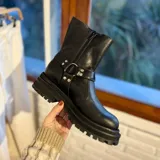 Botas de caña media color negro, confeccionadas en cuero natural, con suela track y plataforma alta. Cuentan con múltiples correas con hebillas metálicas plateadas y tachas decorativas.