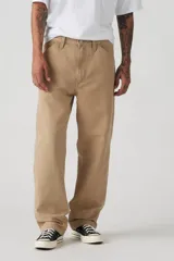 Pantalón de jean color beige, de corte recto y holgado, con bolsillos laterales y traseros.
