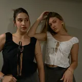 Top corto blanco con escote off-shoulder y lazo ajustable en el centro.