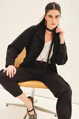 Campera negra de estilo militar o utilitario, con cuello alto, bolsillos delanteros con tapa y cordón ajustable en el ruedo.