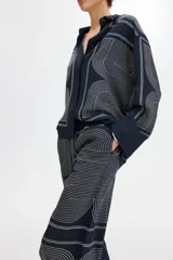 Pantalón de tiro alto color azul marino, confeccionado en tela con leve brillo, con cintura elástica y diseño de piernas rectas con estampado geométrico de líneas claras.