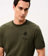 Remera de punto verde militar de manga corta y cuello redondo, elaborada en jacquard. Presenta un diseño de rosa en contraste en la espalda.