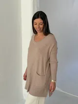 Sweater de punto color visón con cuello en V, mangas largas con puños acanalados y bolsillos frontales tipo parche.