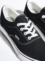 Championes de lona color azul grisáceo, estilo skate o casual, con cordones blancos y suela de goma blanca con una línea fina azul en el borde.