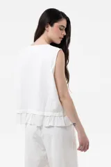 Blusa sin mangas color marrón claro, de corte relajado, con cierre frontal de botones y detalle de volado en el ruedo.