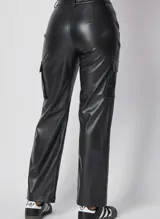 Pantalón cargo de tiro medio confeccionado en cuero sintético negro, con diseño de corte recto, bolsillos laterales tipo cargo con solapa y costuras verticales decorativas en el frente.