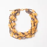 Collar de múltiples hilos con cuentas de resina en tonos amarillos y cuentas cilíndricas en color marrón oscuro, con cierre de mosquetón metálico dorado.