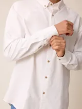 Camisa de manga larga confeccionada en algodón oxford, con cuello abotonado y cierre frontal de botones. Presenta un diseño clásico y minimalista con un pequeño logo bordado en el pecho.