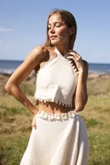 Top halter amarillo pálido de lino, con tiras cruzadas y terminación de mini ojalillos en el escote.