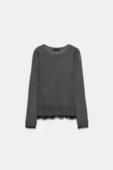 Jersey de cuello redondo y manga larga, confeccionado en tejido de punto fino. Presenta un diseño minimalista con un detalle de aplicación de encaje a tono en el bajo y en los puños.