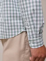 Camisa de manga larga para hombre, confeccionada en algodón con efecto peach (textura suave). Presenta un estampado de cuadros vichy en tonos azul marino y blanco, cuello con botones y un bolsillo de parche en el pecho izquierdo.