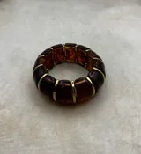Pulsera elástica de diseño modular compuesta por piezas de resina con efecto marmolado y separadores metálicos dorados.