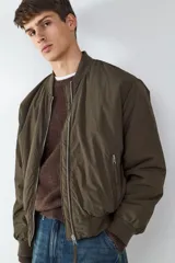Campera tipo bomber acolchada en color verde militar, con cuello redondo, cierre frontal de cremallera metálica y bolsillos laterales con cierre. Presenta puños y bajo elásticos para un ajuste cómodo.