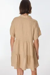 Vestido corto azul de lino italiano con cuello Peter Pan con detalle de encaje, escote en V con botones frontales y corte imperio con volados en la falda. Mangas cortas tipo mariposa.