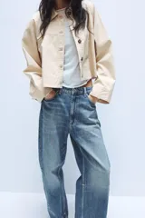 Jeans de tiro medio con diseño baggy barrel, confeccionados en denim color beige con efecto lavado. Presentan cinco bolsillos, costuras laterales torcidas y cierre frontal con cremallera y botón metálico.