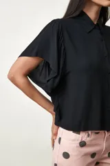 Camisa Girasol de manga corta color negro, con cuello camisero, cierre frontal de botones y mangas con volados drapeados.
